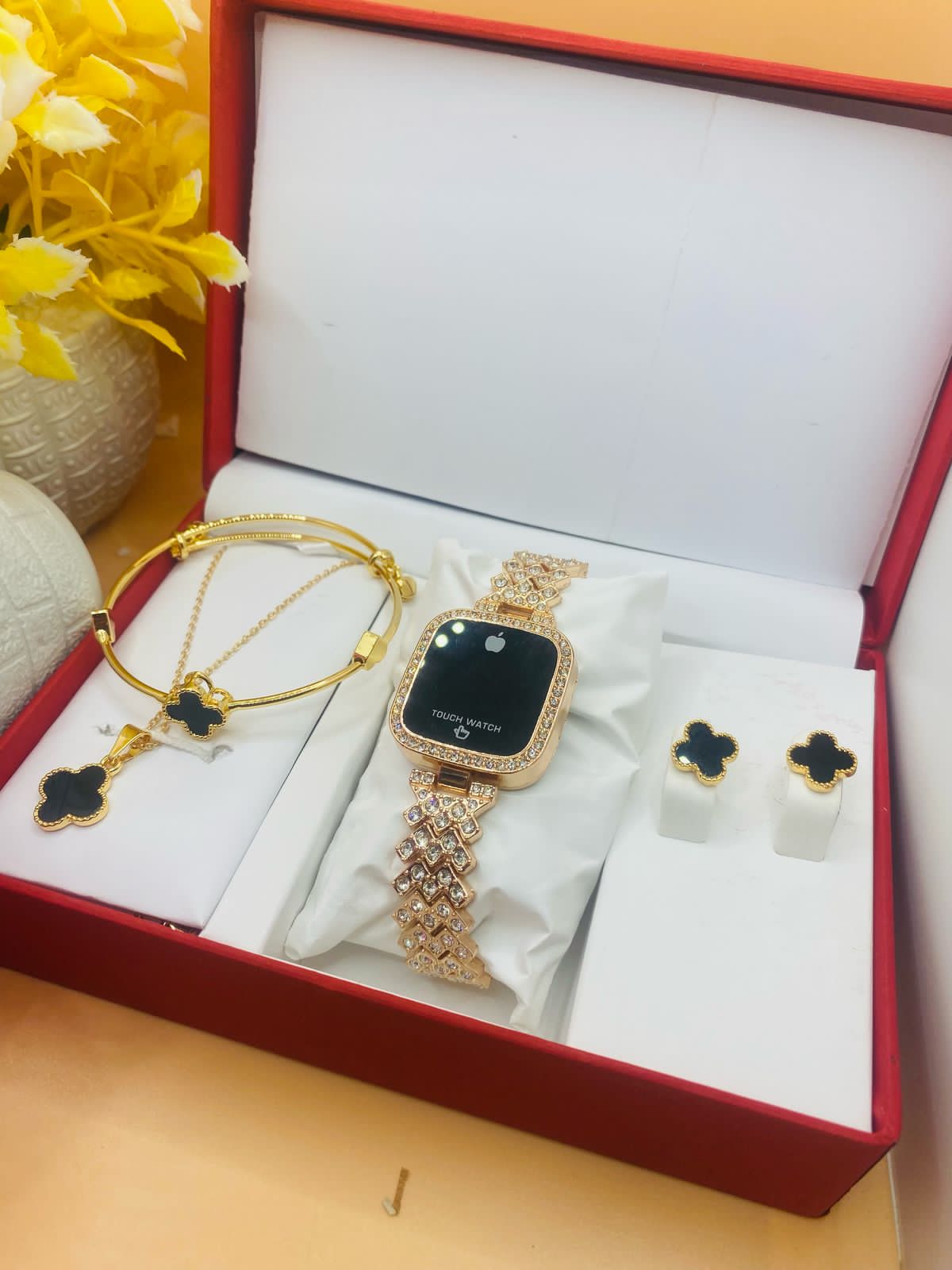 Gold watch, bracelet, and earrings set in a jewelry box with decorative elements.